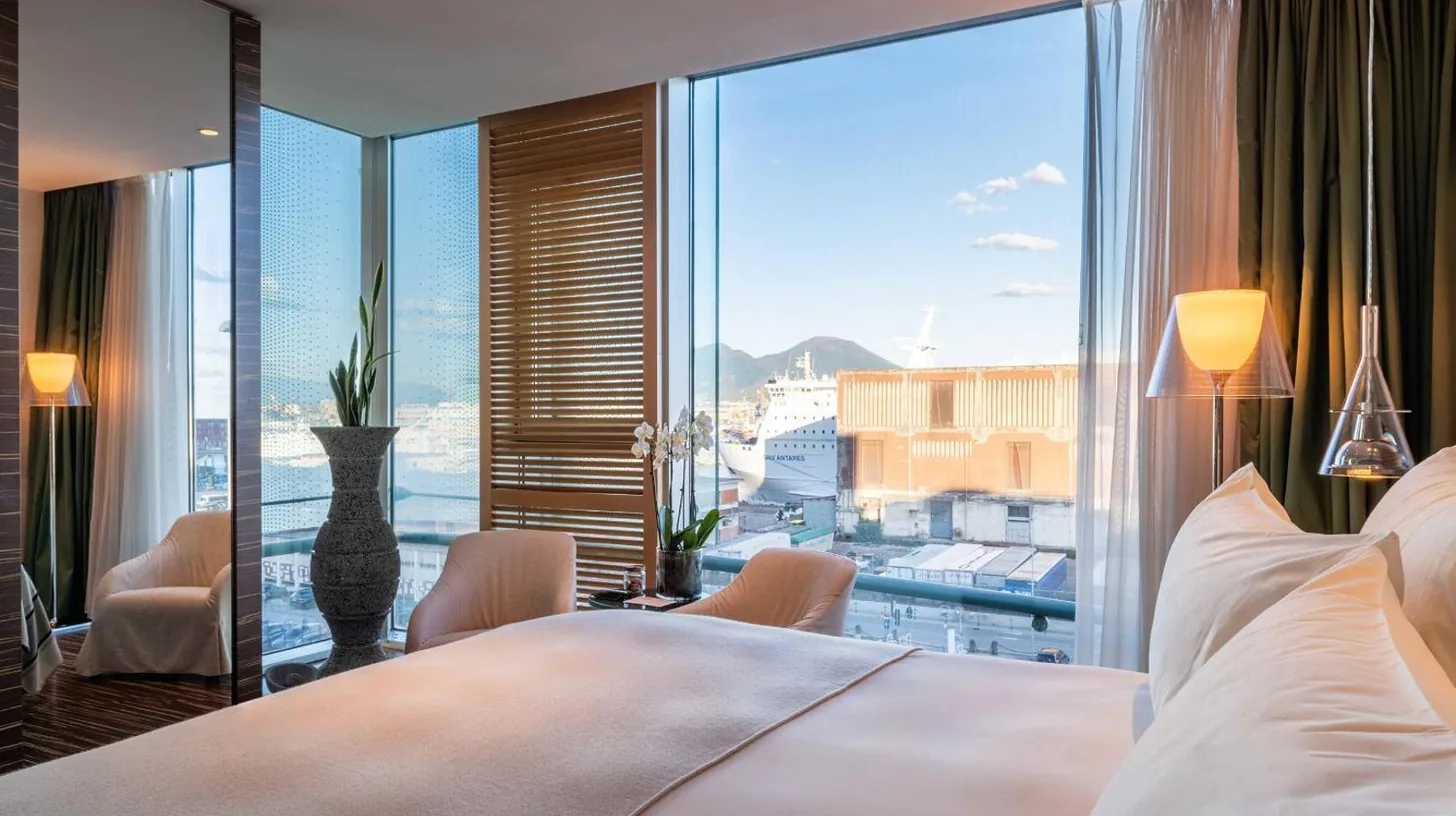 une chambre avec un grand lit et une grande fenÃªtre au ROMEO Napoli Ã  Naples