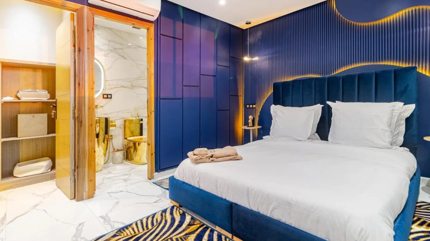 une chambre avec un grand lit à tête de lit bleue at Penthouse rooftop avec jacuzzi vue mer & Hassan II in Casablanca