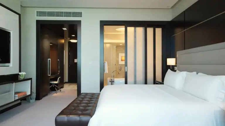 a bedroom with a large white bed and a television at Rosewood Abu Dhabi in Abu Dhabi