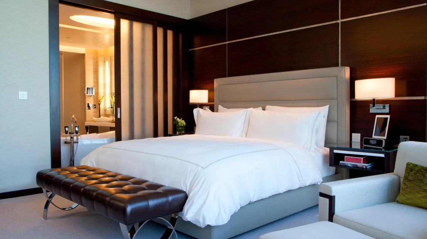 a bedroom with a large white bed and a chair at Rosewood Abu Dhabi in Abu Dhabi