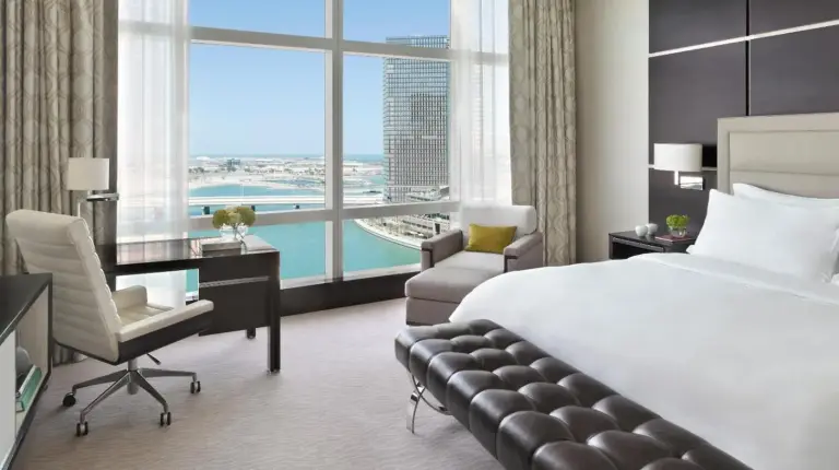 a bedroom with a large bed and a large window at Rosewood Abu Dhabi in Abu Dhabi