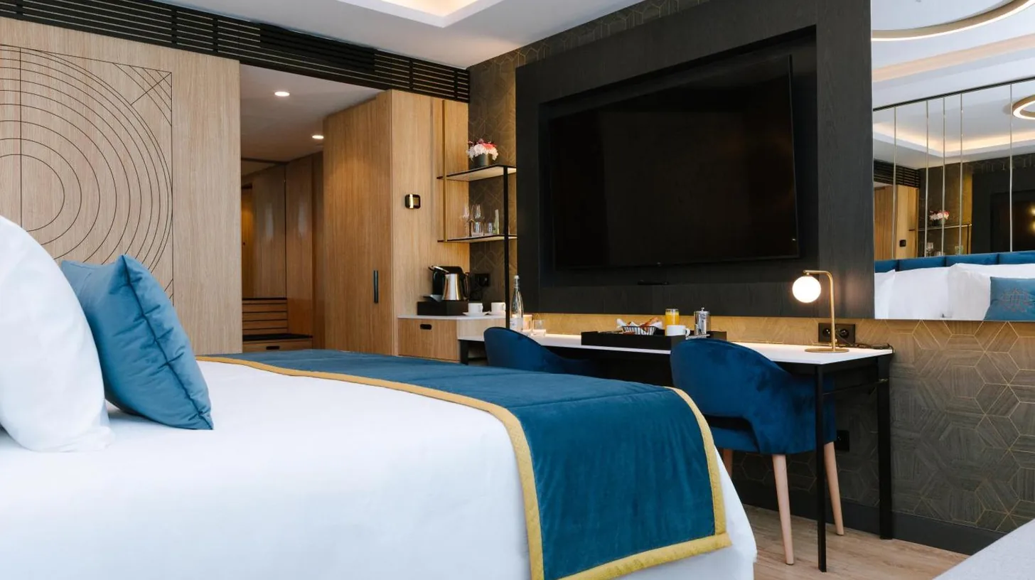 une chambre avec un lit, un bureau et une télévision au Royal Hideaway Casablanca à Casablanca