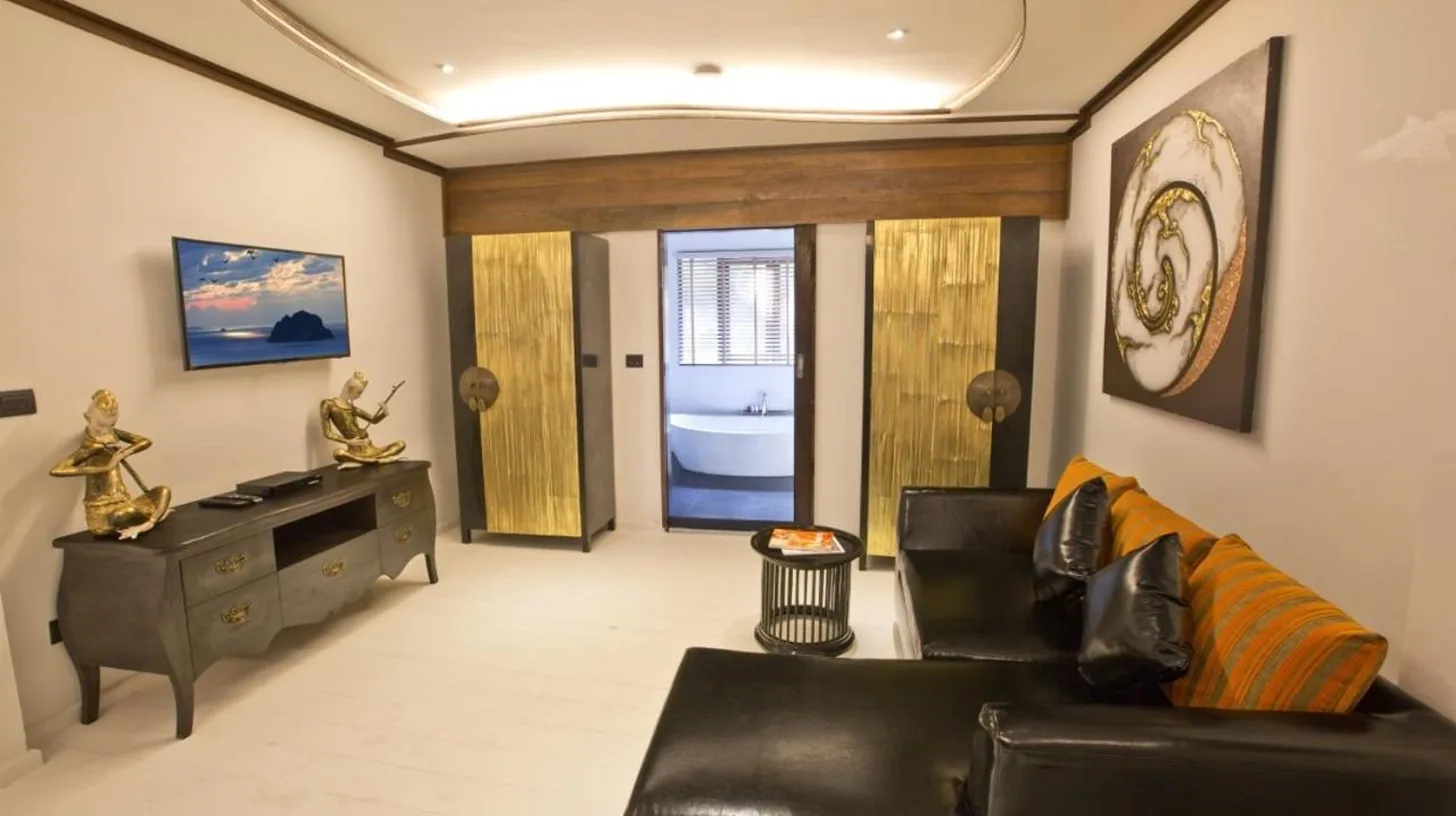 a living room with a black leather couch and a table at Royal Majestic Grand Thai Villa in Choeng Mon Beach