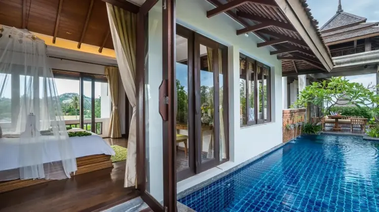 a bedroom with a white bed with a canopy at Royal Muang Samui Villas in Choeng Mon Beach
