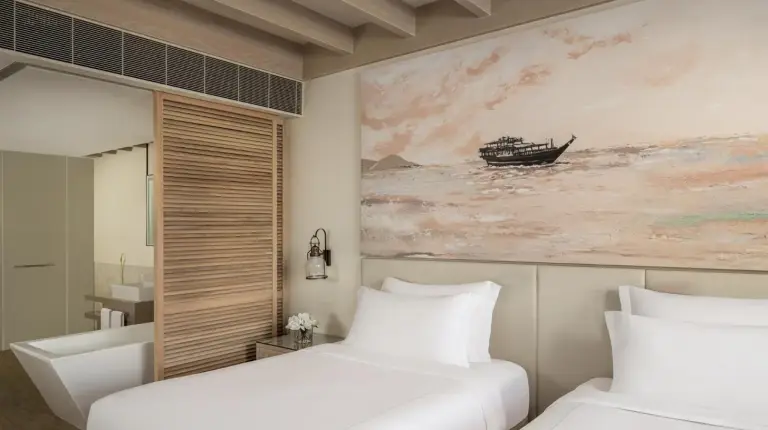 a bedroom with two beds and a painting of a boat at Saadiyat Rotana Resort and Villas in Abu Dhabi