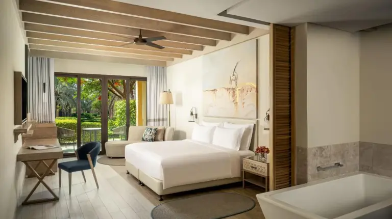 a bedroom with a white bed and a tub at Saadiyat Rotana Resort and Villas in Abu Dhabi