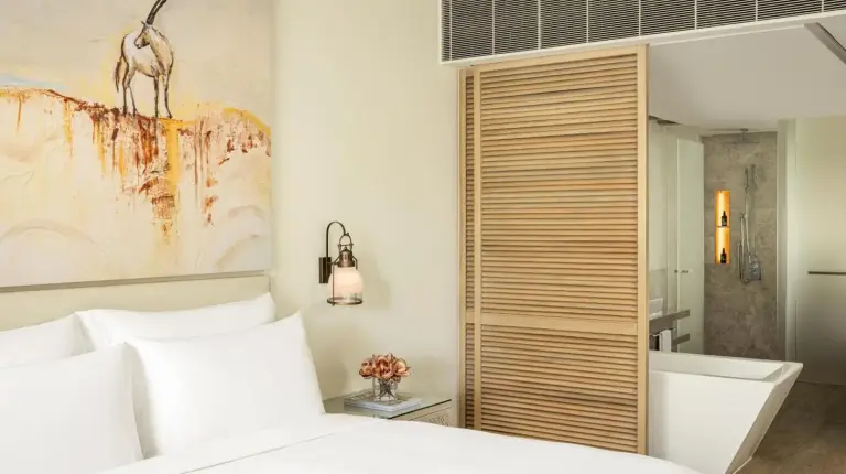 a bedroom with a white bed and a bathroom at Saadiyat Rotana Resort and Villas in Abu Dhabi