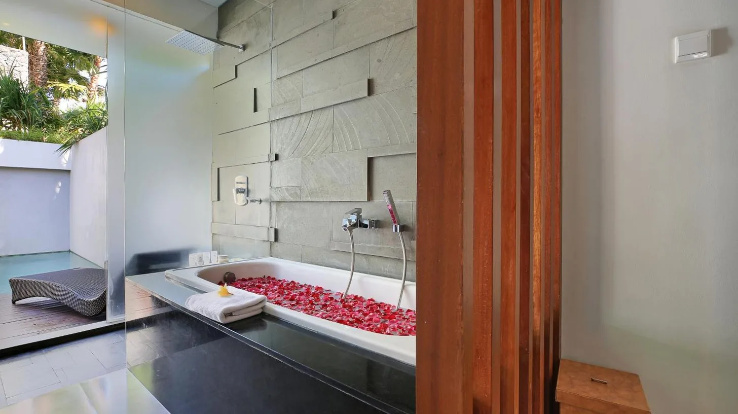 ein Bad mit einer Badewanne voller roter Steine bei Samaja Villas Seminyak in Seminyak