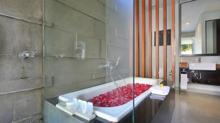 ein Bad mit einer Badewanne voller roter Steine bei Samaja Villas Seminyak in Seminyak
