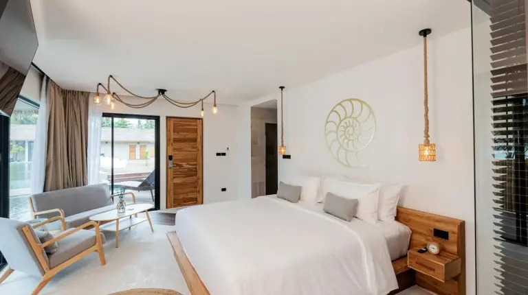 a bedroom with a large white bed and a chair at Samaraya Wellness Resort - Adults Only in Lipa Noi