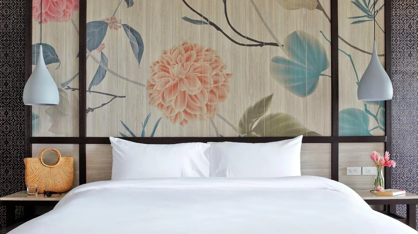a bedroom with a white bed and a floral wall at Sareeraya Villas & Suites in Chaweng