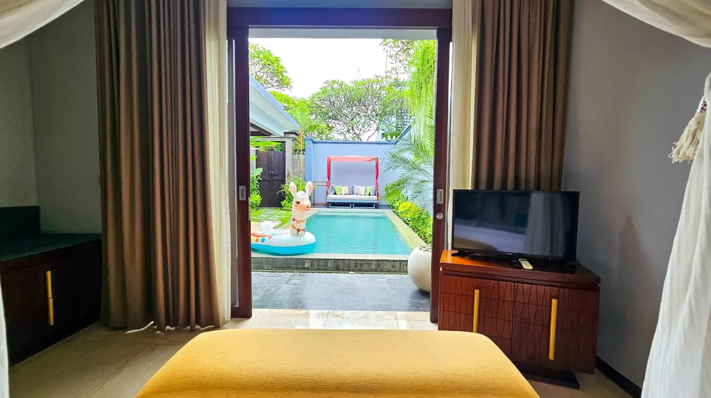 un dormitorio con un televisor y una piscina en Seminyak Icon - by Karaniya Experience - CHSE certified en Seminyak