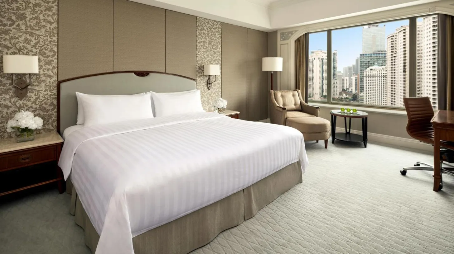 a bedroom with a large bed and a large window at Shangri-La Jakarta in Jakarta