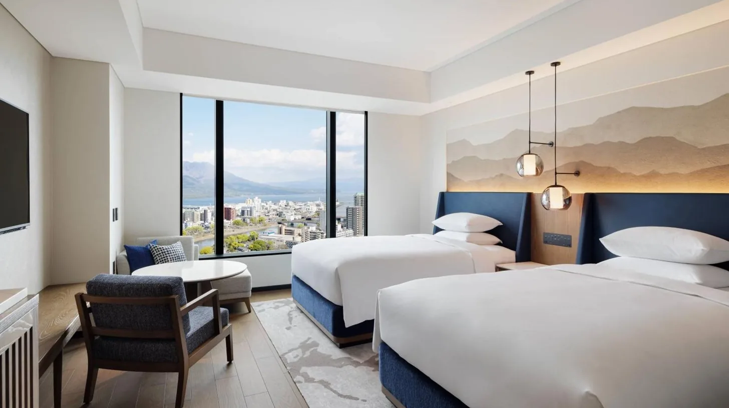 a hotel room with two beds and a window at Sheraton Kagoshima in Kagoshima