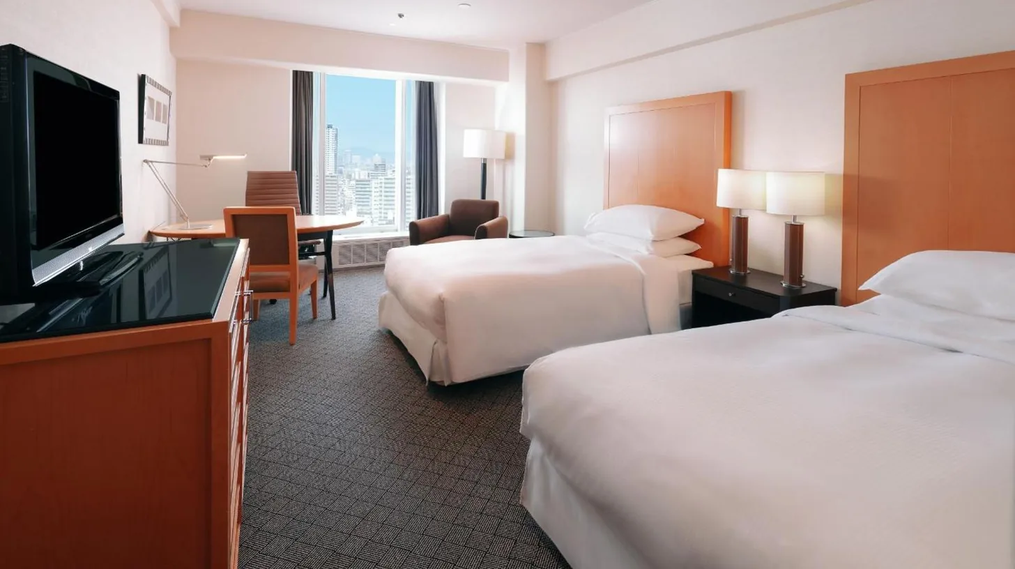 a hotel room with two beds and a desk with a table at Sheraton Miyako Hotel Osaka in Osaka