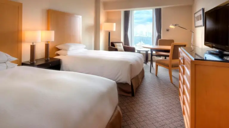 a hotel room with two beds with pillows and a lamp at Sheraton Miyako Hotel Osaka in Osaka