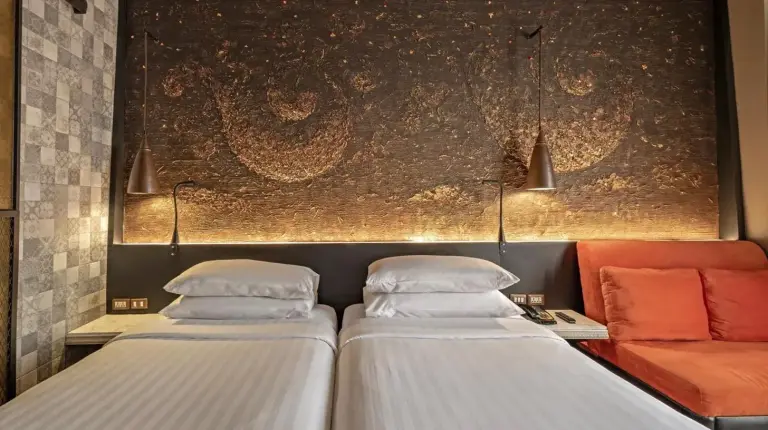 two beds in a room with a couch at Siam At Siam Design Hotel Bangkok in Bangkok