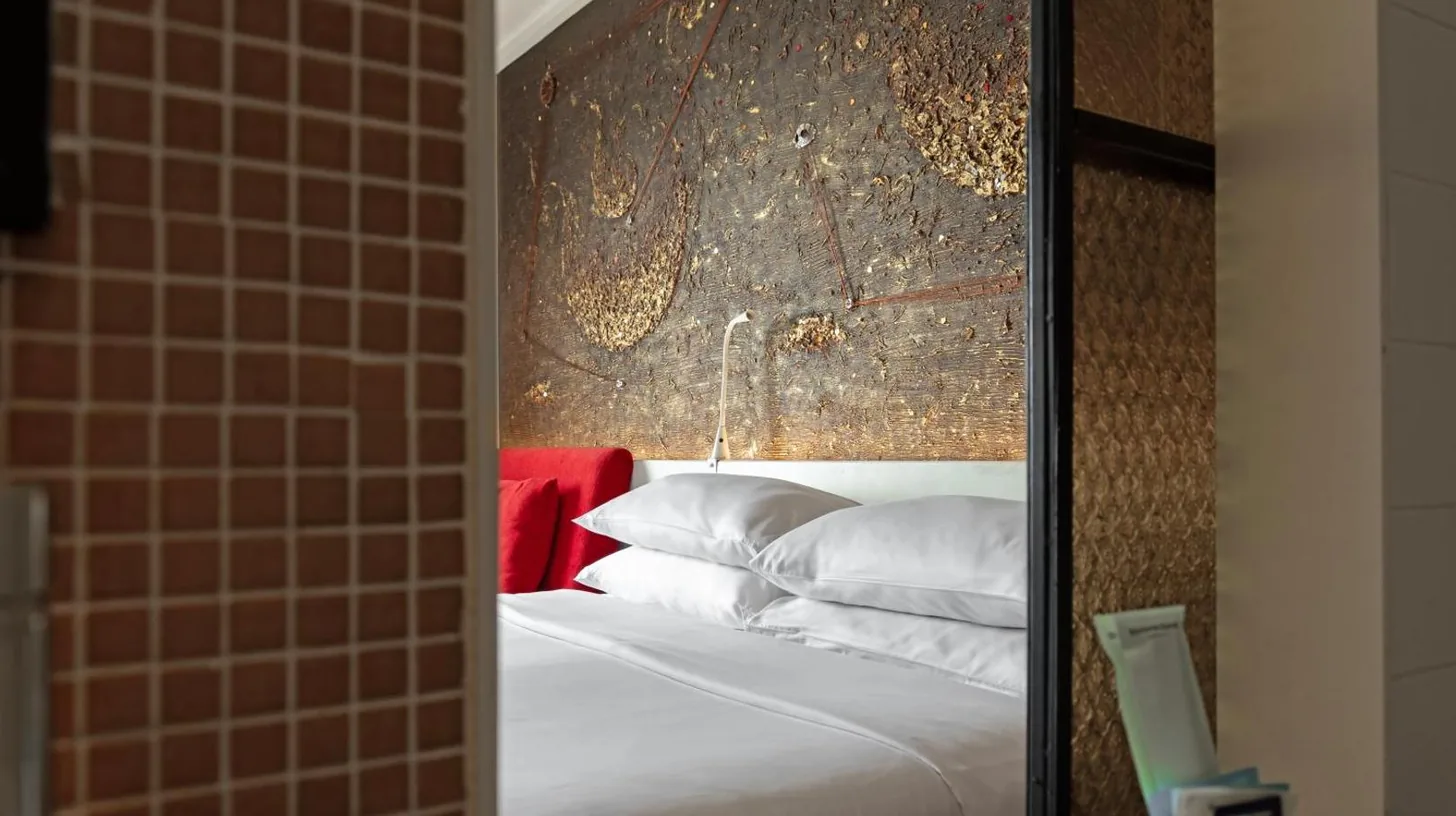 a bedroom with a mirror and a bed with white pillows at Siam At Siam Design Hotel Bangkok in Bangkok