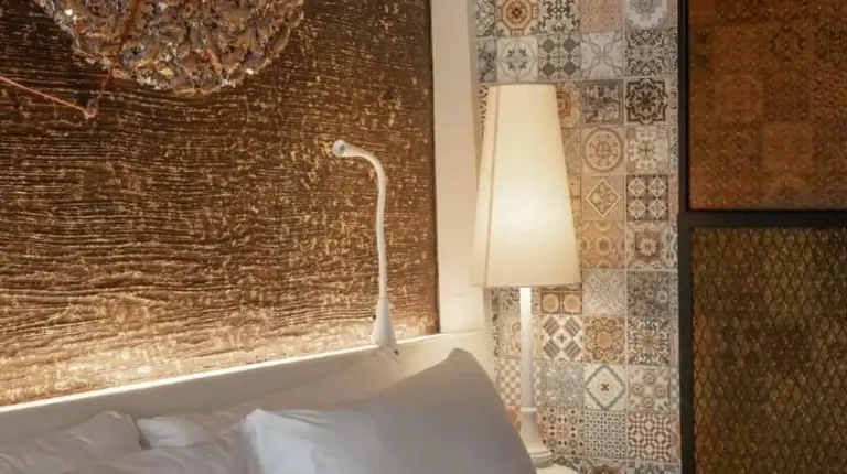 a white bed with a lamp next to a wall at Siam At Siam Design Hotel Bangkok in Bangkok