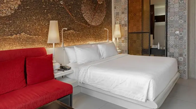 a bedroom with a bed and a red couch at Siam At Siam Design Hotel Bangkok in Bangkok