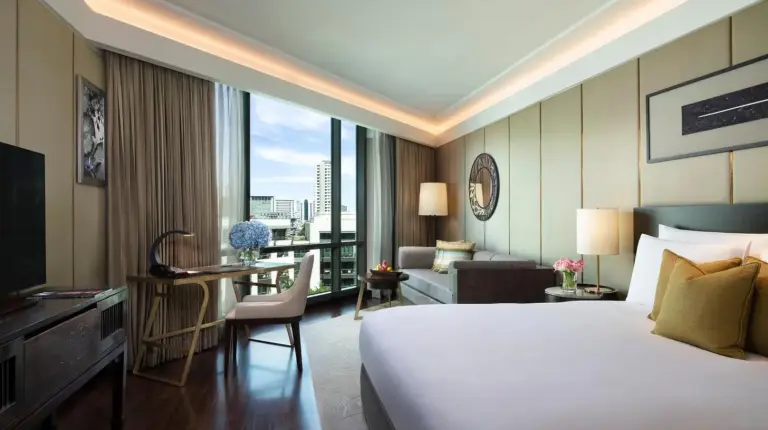 a hotel room with a large bed and a desk and a room at Siam Kempinski Hotel Bangkok in Bangkok