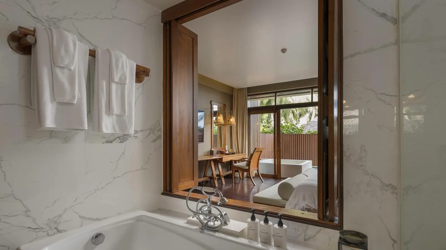 a bathroom with a tub and a large mirror at Silavadee Pool Spa Resort - SHA Extra Plus in Lamai