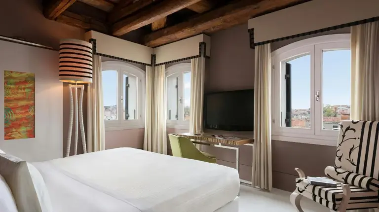 a bedroom with a bed and a chair and windows at Sina Centurion Palace in Venice