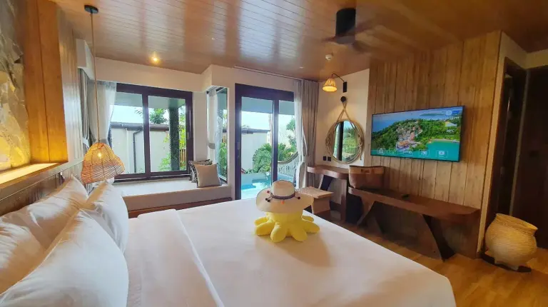 a teddy bear sitting on a bed in a room at SINAE Phuket Luxury Hotel in Phuket Town