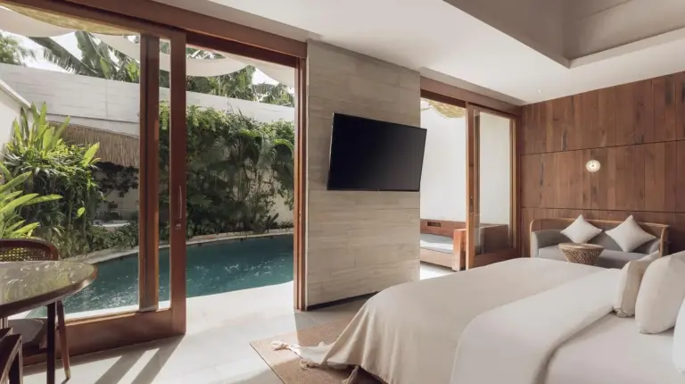 a bedroom with a large white bed and wooden walls at Sini Vie Resort & Spa Seminyak by Ini Vie Hospitality in Seminyak