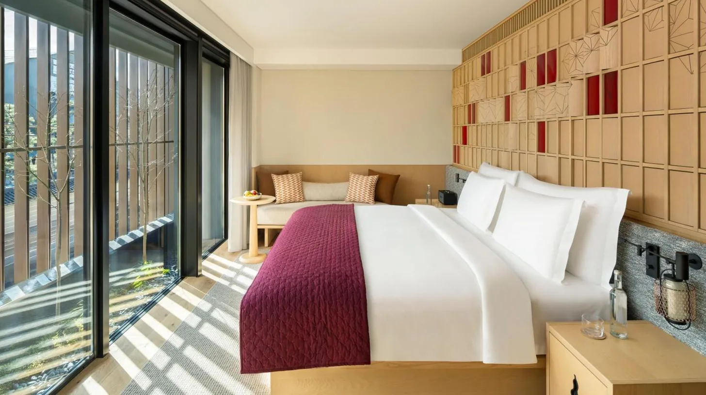 a bedroom with a large bed and a balcony at Six Senses Kyoto in Kyoto