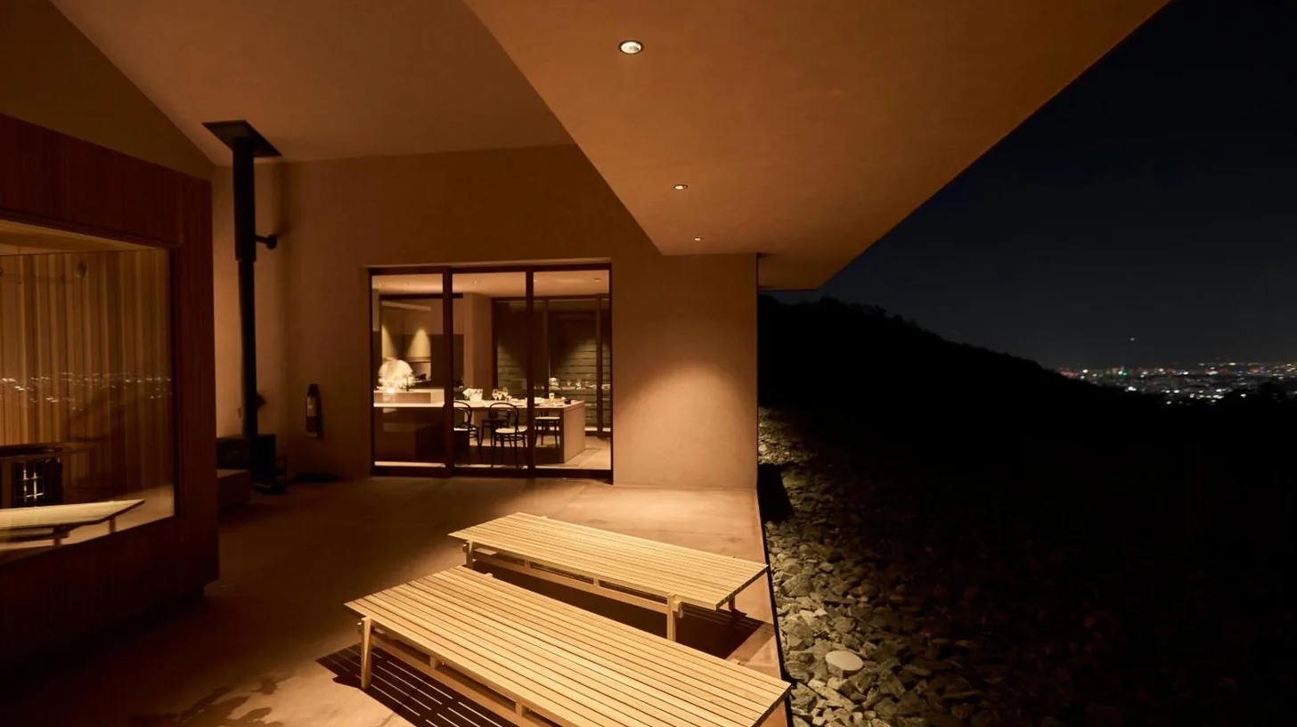 two benches on the side of a building at night at Snow Peak YAKEI SUITE ABURAYAMA FUKUOKA in Fukuoka