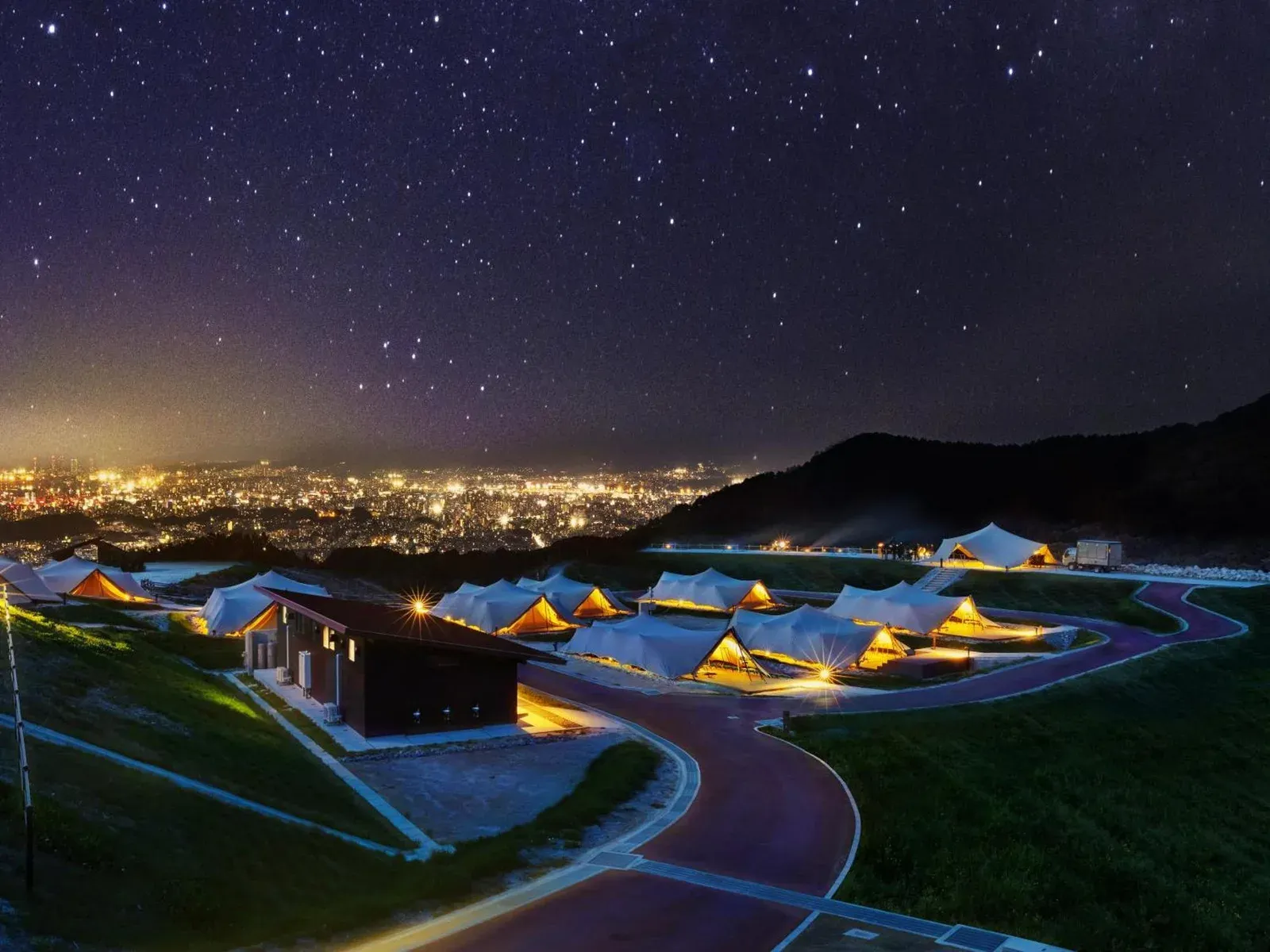 Elegant night view of Snow Peak YAKEI SUITE ABURAYAMA FUKUOKA showcasing glamping tents and city lights