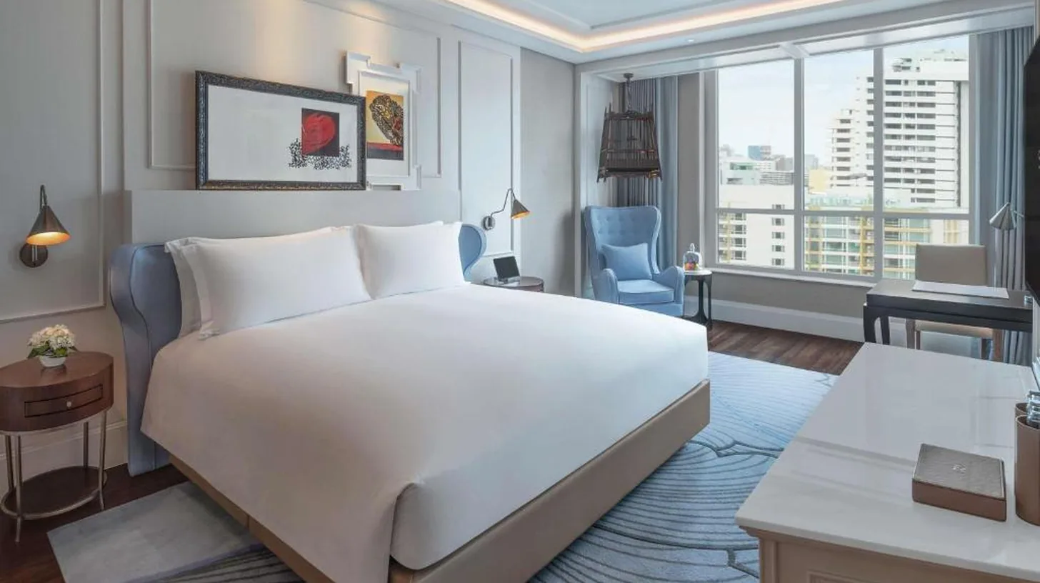 une chambre avec un grand lit blanc et un bureau au Sofitel Bangkok Sukhumvit à Bangkok