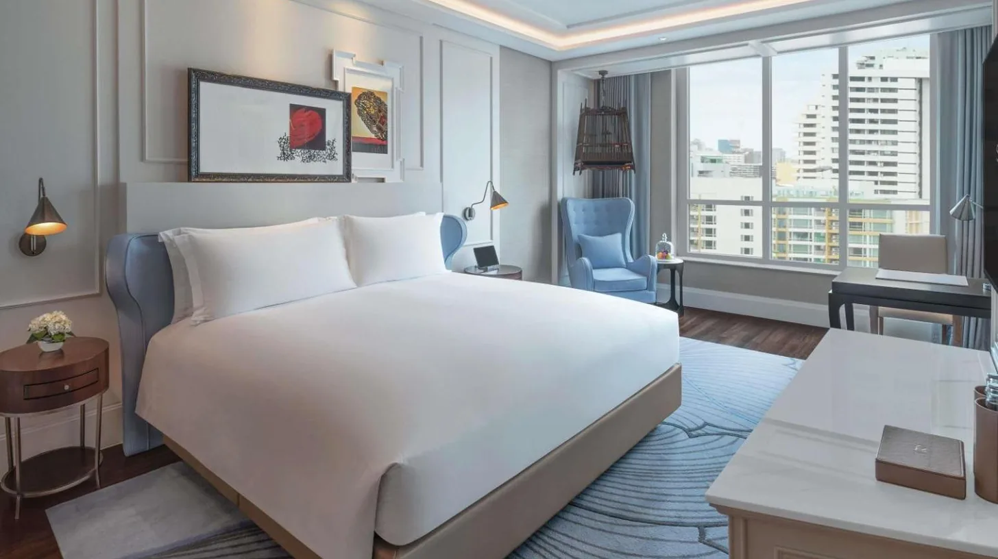 une chambre avec un grand lit blanc et une chaise bleue au Sofitel Bangkok Sukhumvit à Bangkok