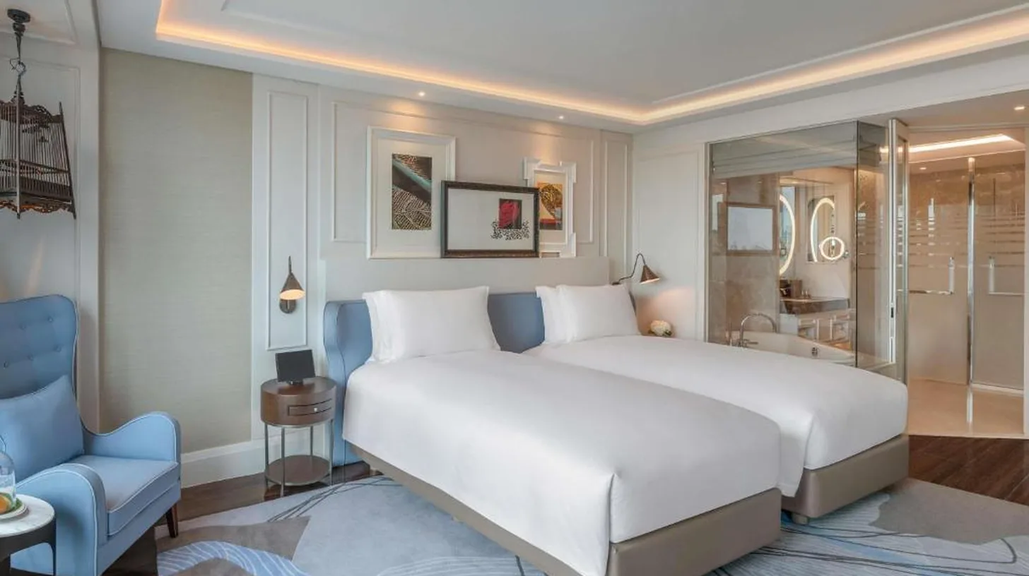 une chambre d'hôtel avec un lit et une chaise bleue au Sofitel Bangkok Sukhumvit à Bangkok