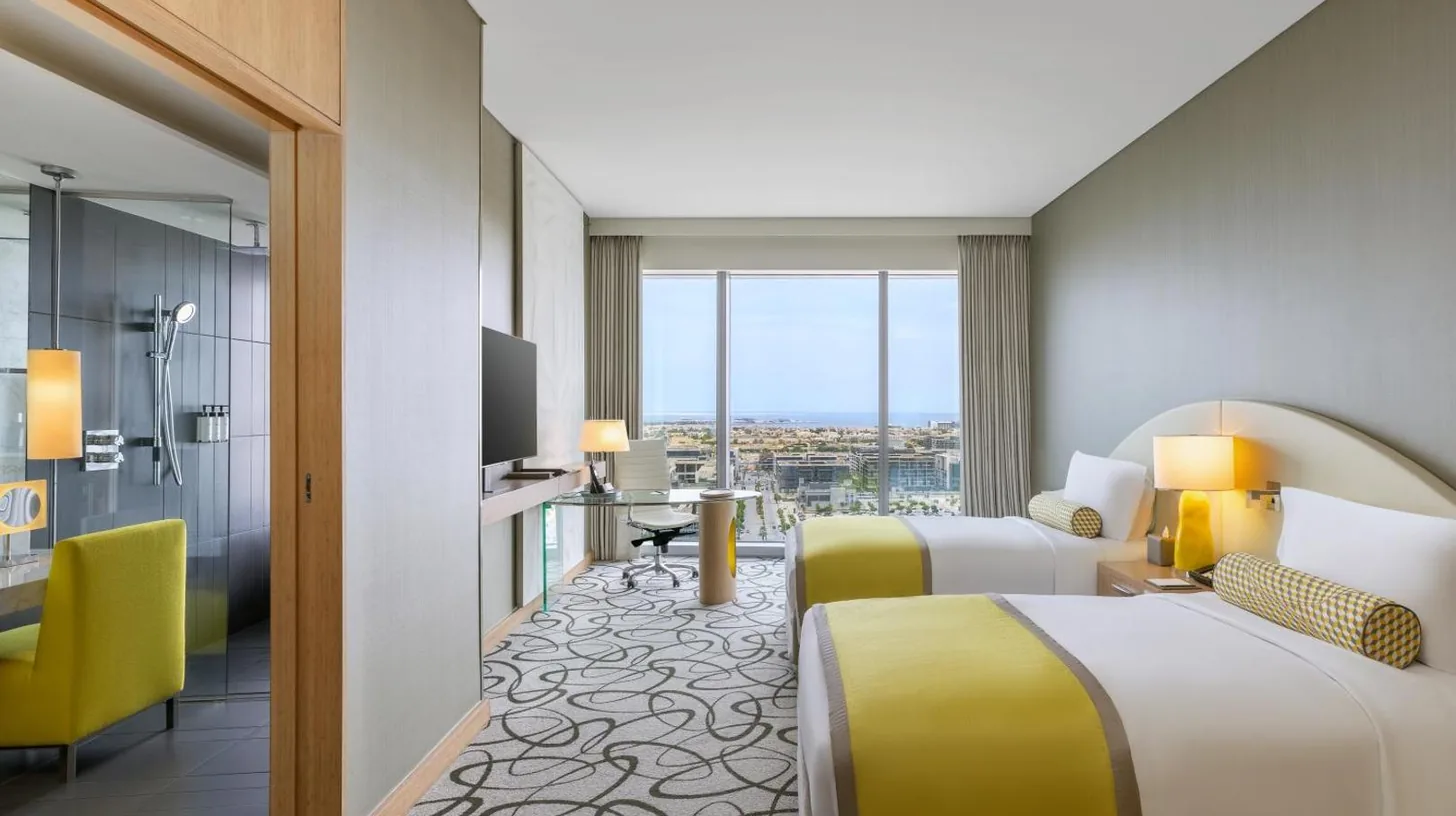 a living room with blue furniture and a large window at Sofitel Dubai Downtown in Dubai
