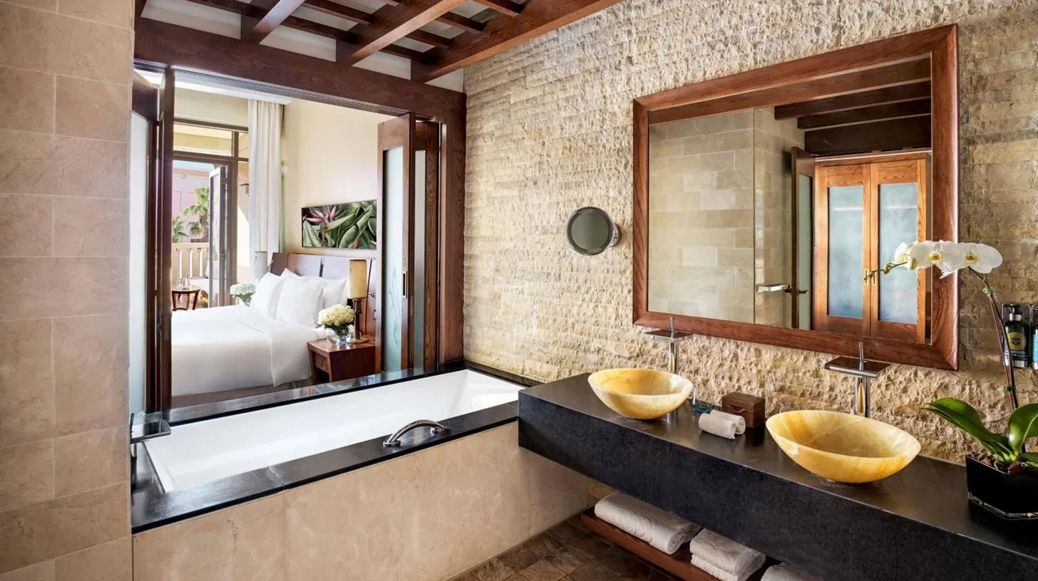 une salle de bain avec un lit blanc et un grand miroir au Sofitel Dubai The Palm Resort & Spa à Dubaï