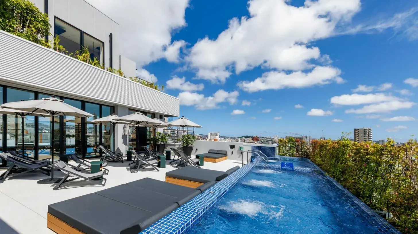 a swimming pool with chaise lounge chairs and a building at Southwest Grand Hotel in Naha