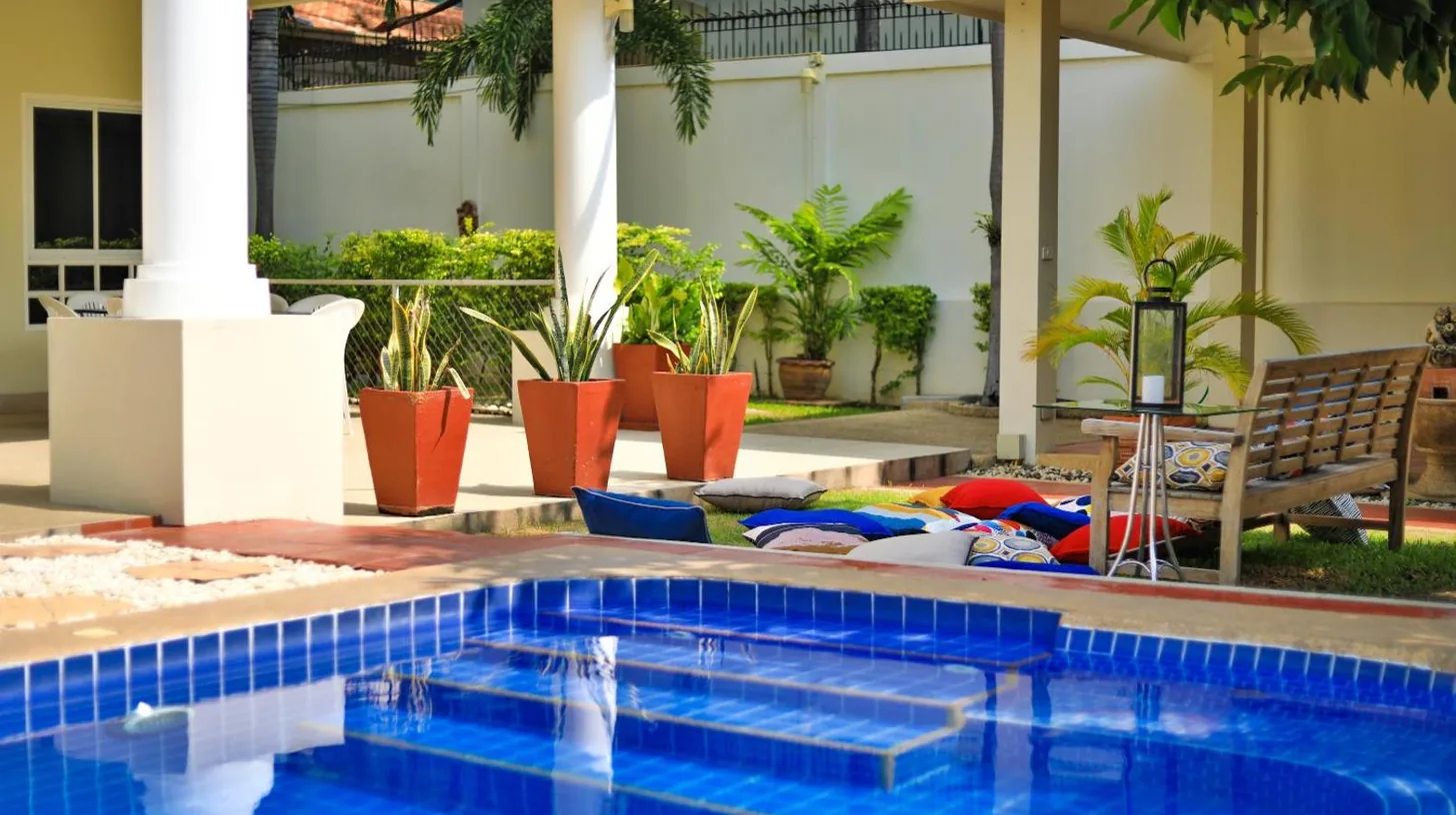 two chairs and a table next to a swimming pool at Sweet Villas Pattaya in Pattaya South