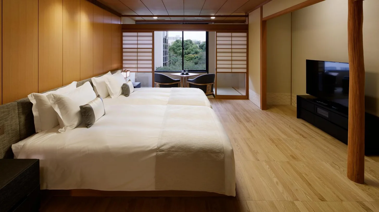 a bedroom with a large white bed and a television at Takanawa Hanakohro