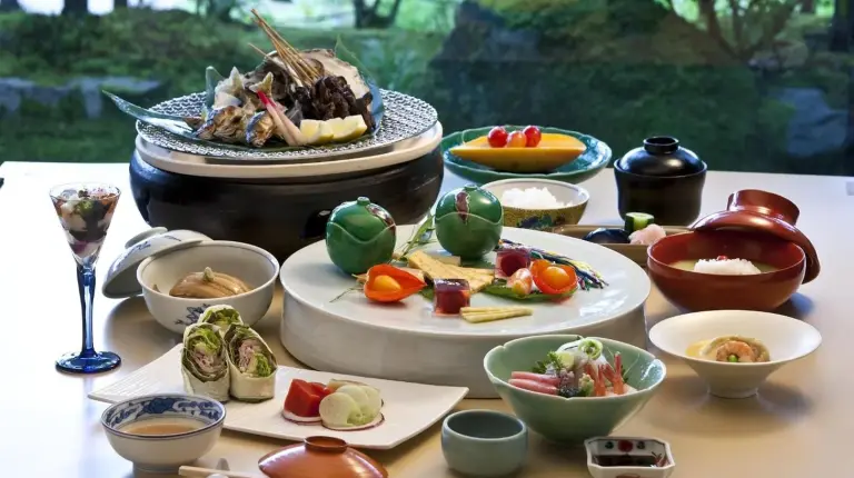 a table with plates of food and bowls of food at TAKITEI Riverside Onsen ーEin verstecktes Ryokan in Kanazawaー in Kanazawa