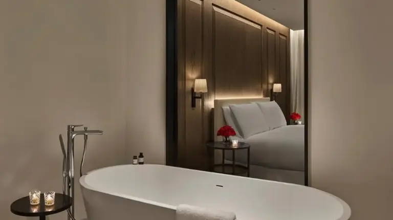 a white bath tub in a bathroom with a mirror at The Abu Dhabi EDITION in Abu Dhabi