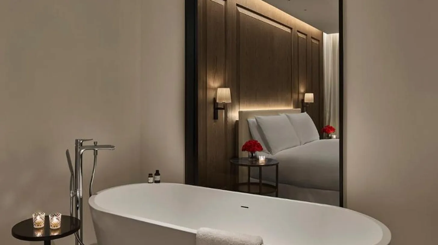 a white bath tub in a bathroom with a mirror at The Abu Dhabi EDITION in Abu Dhabi