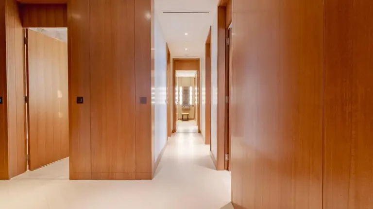 a hallway with wooden doors and a hallway with white floors at The Address Residences Dubai Opera - Luxury 3BR Stay with Stunning Burj Khalifa & Fountain Views in Dubai