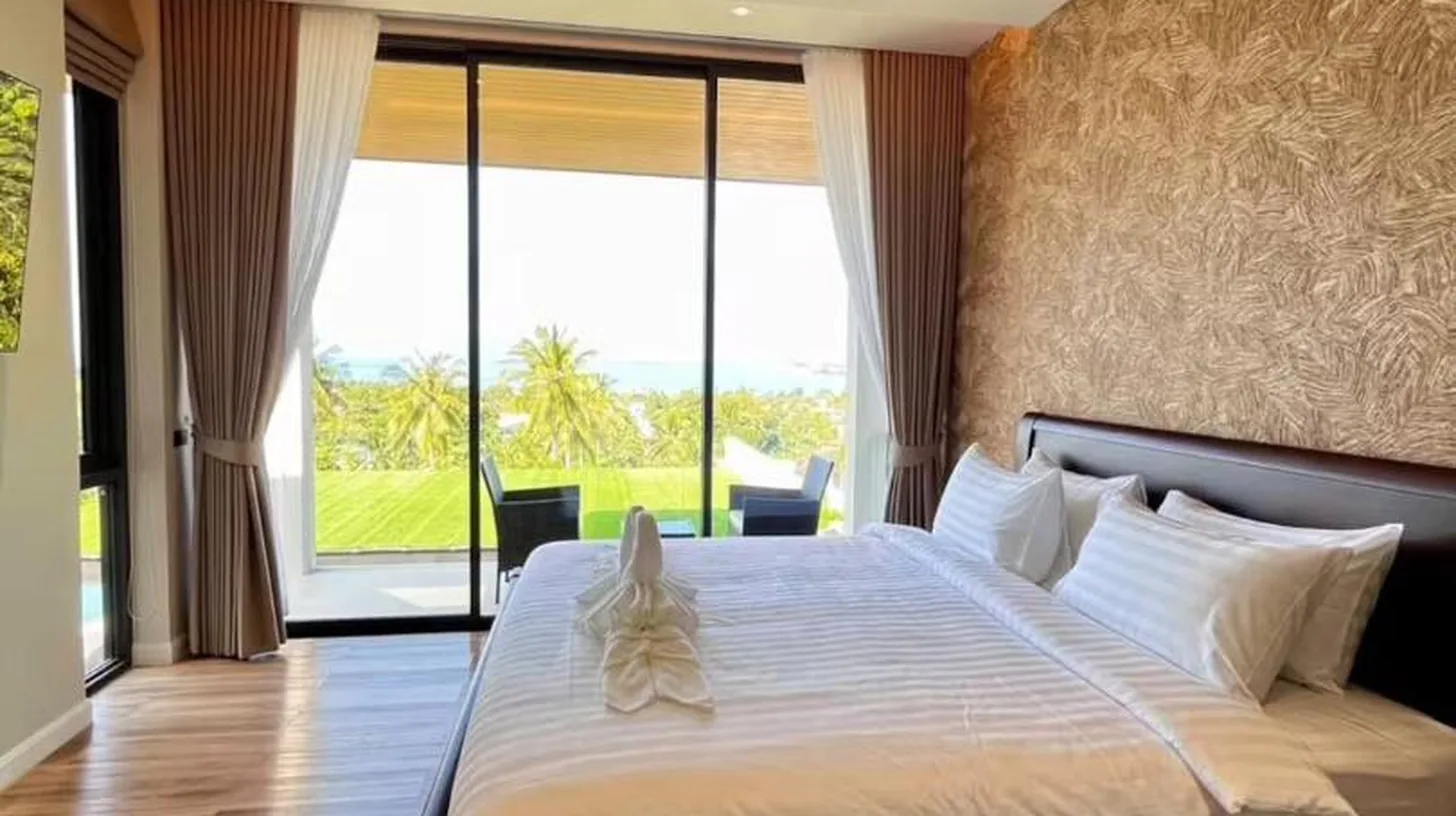 a bedroom with a large bed with a large window at The Akbar Villa in Bang Rak Beach