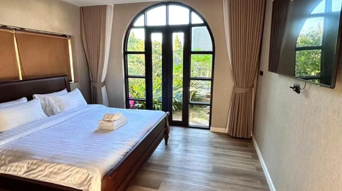 a bedroom with a bed and a large window at The Akbar Villa in Bang Rak Beach