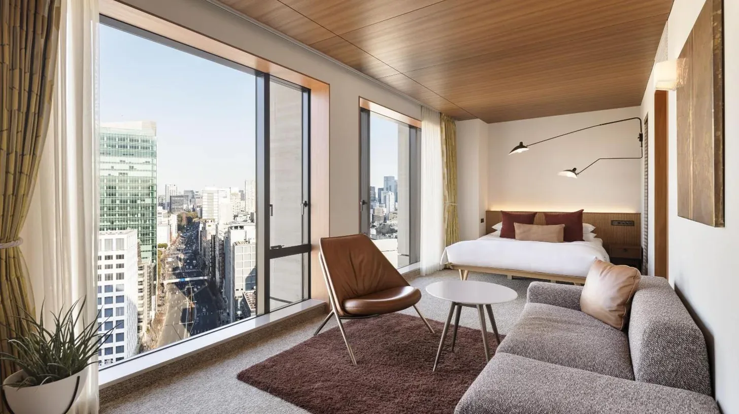a living room with a couch and a bed and a large window at THE AOYAMA GRAND HOTEL in Tokyo
