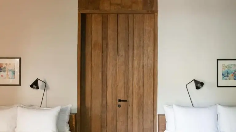 ein Schlafzimmer mit zwei Betten und einer Holztür im The Asa Maia - Bespoke Wellness Resort in Uluwatu