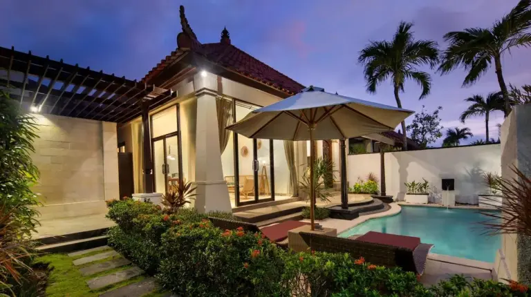 a house with a swimming pool and an umbrella at The Club Villas Seminyak in Seminyak