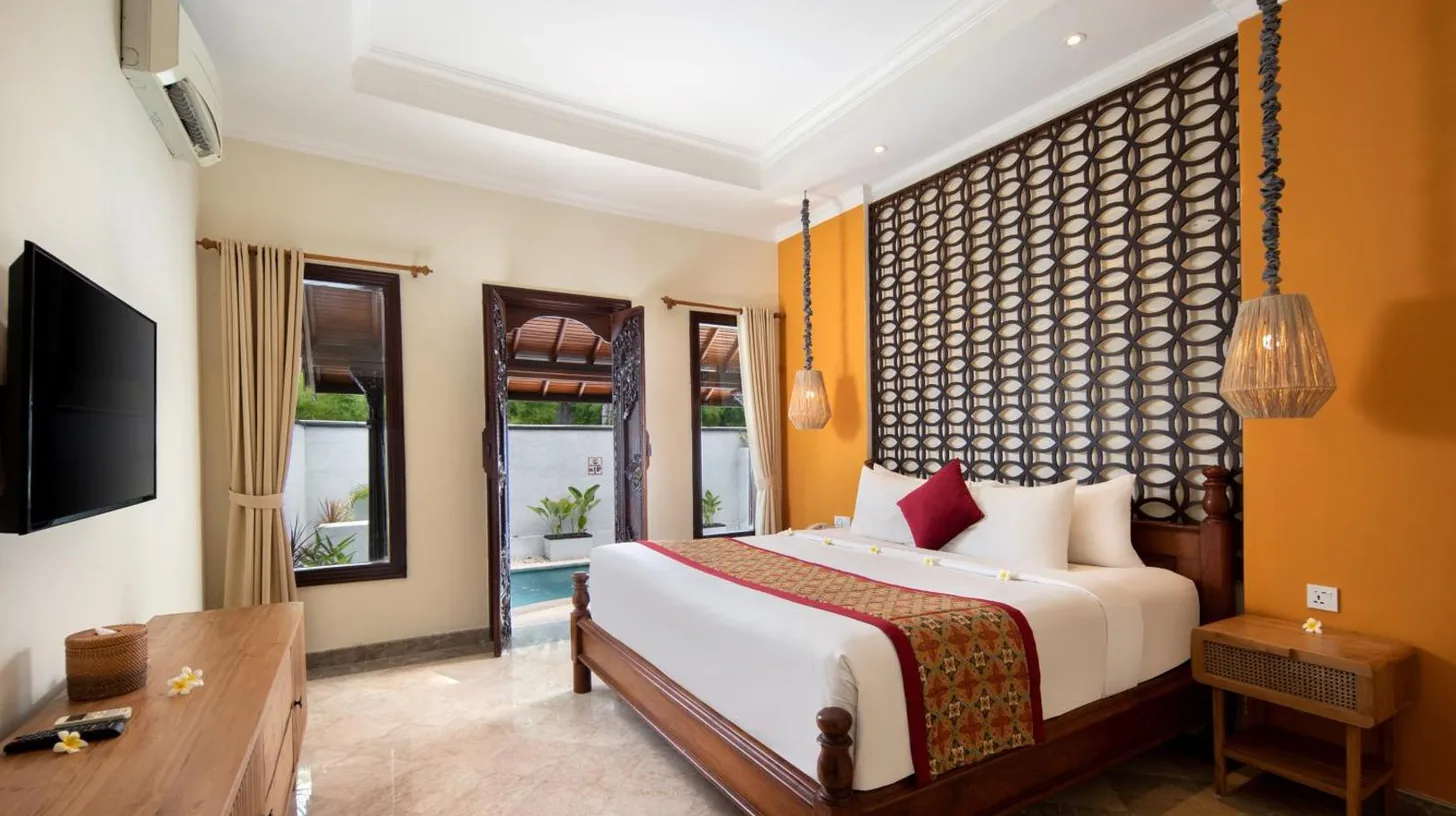a bedroom with a bed and a desk and a television at The Club Villas Seminyak in Seminyak